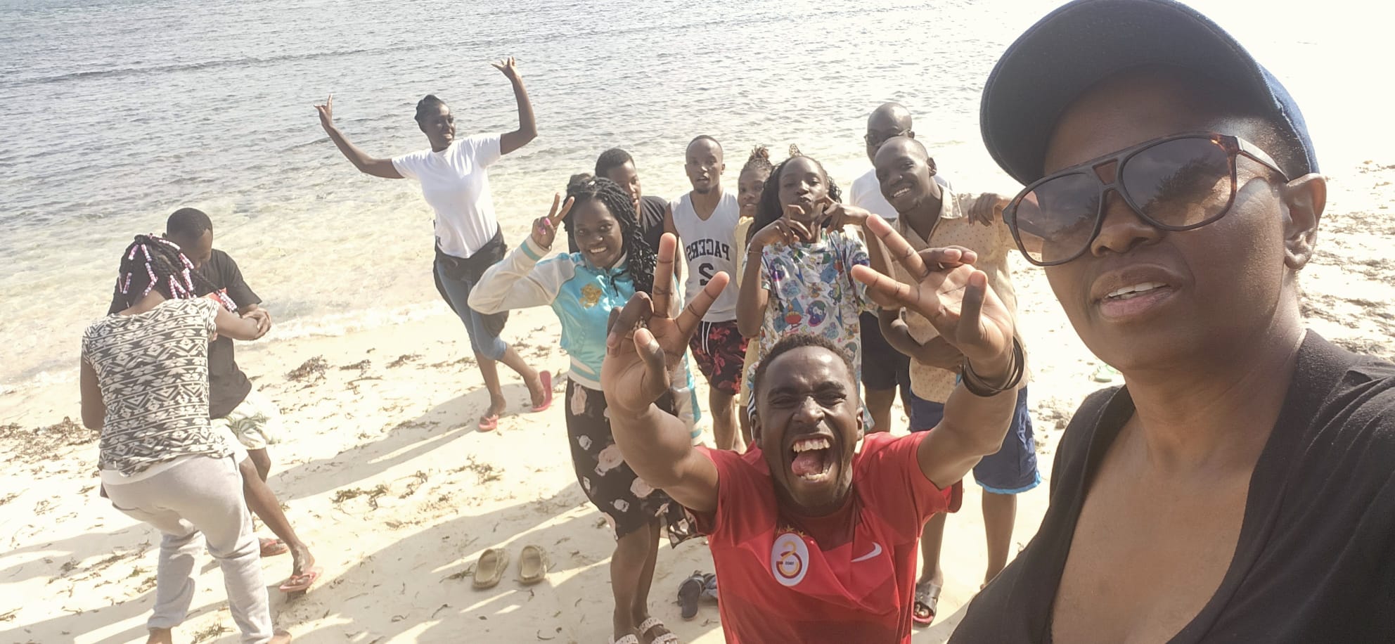 KAI youth celebrating at beach retreat - hands raised in joy